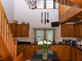 A kitchen with wooden cabinets and a vase of flowers at Higher Wadden Farm Southleigh