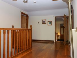 A hallway with a wooden banister and framed pictures at Higher Wadden Farm Southleigh