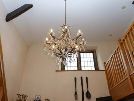 A chandelier hanging in a room with utensils on the wall at Higher Wadden Farm Southleigh