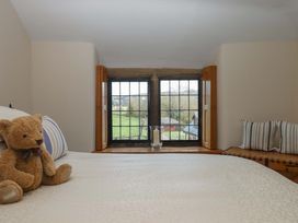 A bedroom with a teddy bear and window view at Higher Wadden Farm Southleigh