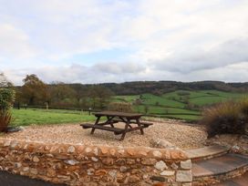 A picnic table on gravel with stone wall and hills at Higher Wadden Farm in Southleigh