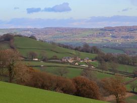A landscape view with hills and a farm at Higher Wadden Farm Southleigh