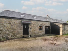 An outdoor view of a stone building with a garage at Riverside Barn in Stithians