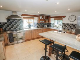 A kitchen with countertop and bar stools at Riverside Barn in Stithians