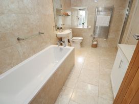 A bathroom with a bathtub, sink, toilet and towel rail at Riverside Barn Stithians