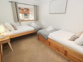 A bedroom with two single beds and a window at Riverside Barn Stithians