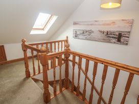 A hallway with a staircase and wall art at Riverside Barn in Stithians