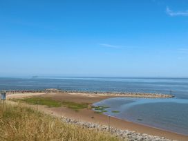A beach with rocks and grass alongside the sea at Ferncliffe in 