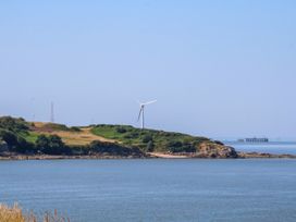 A view of a wind turbine on a hill by the water with a pier in the distance at Ferncliffe in 