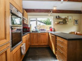 A kitchen with wooden cabinets and appliances at Neuadd Wen Gaerwen