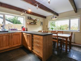A kitchen with wooden cabinets and a dining table at Neuadd Wen in Gaerwen