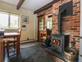 A dining room with a wood stove and table at Neuadd Wen Gaerwen
