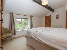 A bedroom with a bed, window, chair and door at Neuadd Wen in Gaerwen