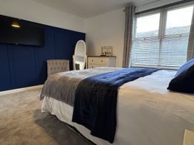 A bedroom featuring a bed, television, mirror, dresser and chair at Ironstone Cottage in Eston