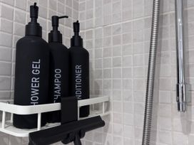 Bottles of shower gel shampoo and conditioner in a bathroom at Ironstone Cottage Eston