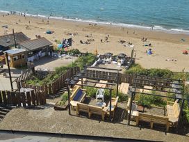 A beach scene with sun umbrellas and seating at Awel Deg in Cardigan