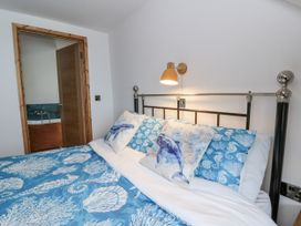 A bedroom with a bed and door leading to a bathroom at Awel Deg, Tresaith