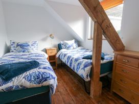 A bedroom with two beds and a nightstand at Awel Deg, Tresaith
