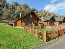 A wooden cabin with a deck and fence at Trevano in St Breward