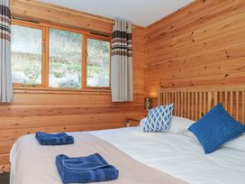 A bedroom with a bed, pillows, towels, and windows at Trevano in St Breward