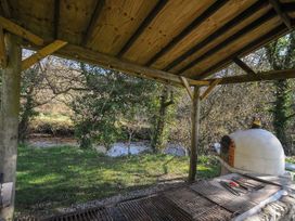 An outdoor area with a wooden structure and grill beside a river at Pencarrow St Breward