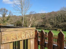 A wooden sign labeled Trebah with a fence and trees in the background at Trebah in St Breward