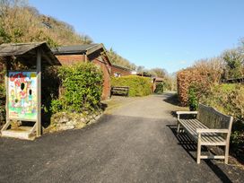 A pathway with a wooden bench and signboard at Trebah in St Breward