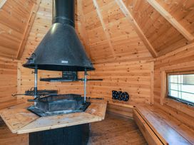 An indoor space featuring a fireplace and grill with wooden benches at Eden in St Breward