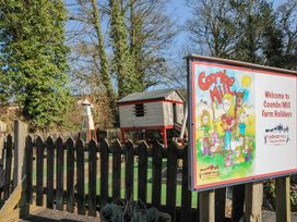 Outdoor area with a sign and play equipment at Coombe Mill in St Breward