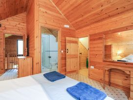 A bedroom with wooden walls and towels on bed at Heligan, St Breward