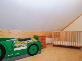 A children's bedroom with a car-shaped bed and a crib at Heligan St Breward
