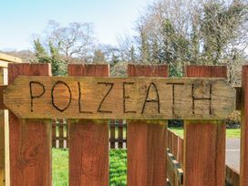 A wooden sign reading Polzeath near a fence at Polzeath in St Breward