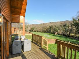 An outdoor deck with a table and chairs overlooking a grassy area at Polzeath in St Breward