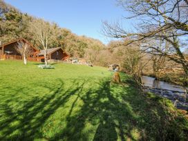 Two wooden cabins with a river and playground at Polzeath in St Breward