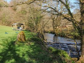 A stream with trees and a shelter in a grassy area at Polzeath in St Breward