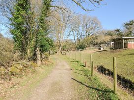A path surrounded by trees and a fence at Polzeath in St Breward