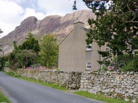 A house with a stone wall beside a road and mountains at Buckbarrow in Seascale