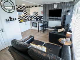 A living room with a sofa and kitchen area at 3 Cherry Blossom in Skegness