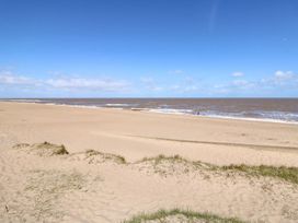 A beach with ocean waves and a person in the distance at 3 Cherry Blossom Skegness