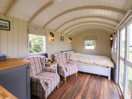 A living room with a bed and two chairs at Shepherds hut