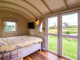 A bedroom with a bed and television at Shepherds hut 