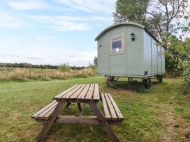A shepherd's hut with a picnic table in an open field at Shepherds hut 