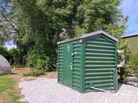 A storage shed with a green exterior in a garden area at Shepherds hut