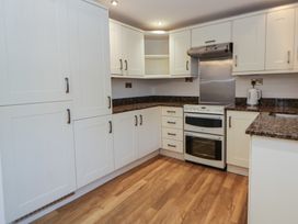 A kitchen with cabinets, stove, and countertop at Cariad Cottage in Hereford
