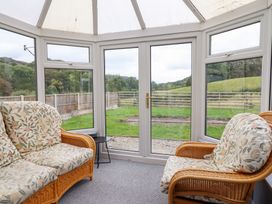 A conservatory with rattan chairs and windows at Plas Yn Bonwm Corwen