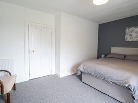 A bedroom with a bed, chair, door, and wall art at Plas Yn Bonwm in Corwen