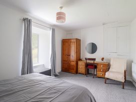 A bedroom with a bed, wardrobe, desk, and window at Plas Yn Bonwm in Corwen