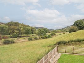 A view of a grassy field with trees and a river at Plas Yn Bonwm in Corwen