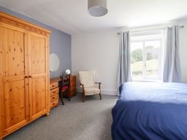A bedroom with a wardrobe, desk, and bed at Plas Yn Bonwm in Corwen