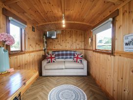 A snug with a couch and wooden table at Sharon's Shepherd Hut in Oswestry